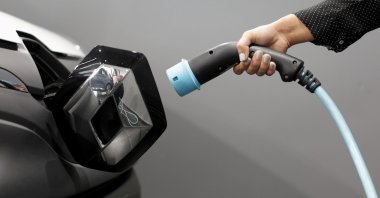A woman holds a cable to charge a Renault Kangoo ZE electric utility vehicle at a Renault dealership in Cagnes-Sur-Mer, France, Oct. 22, 2020. (Reuters Photo)