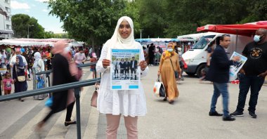 French local election candidate Sara Zemmahi, wearing a headscarf, holds her campaign flyer with the slogan "Different, but united for you" as she poses during an interview for Reuters ahead of the upcoming French local elections in the La Mosson market in Montpellier, France, June 5, 2021. (Reuters Photo)