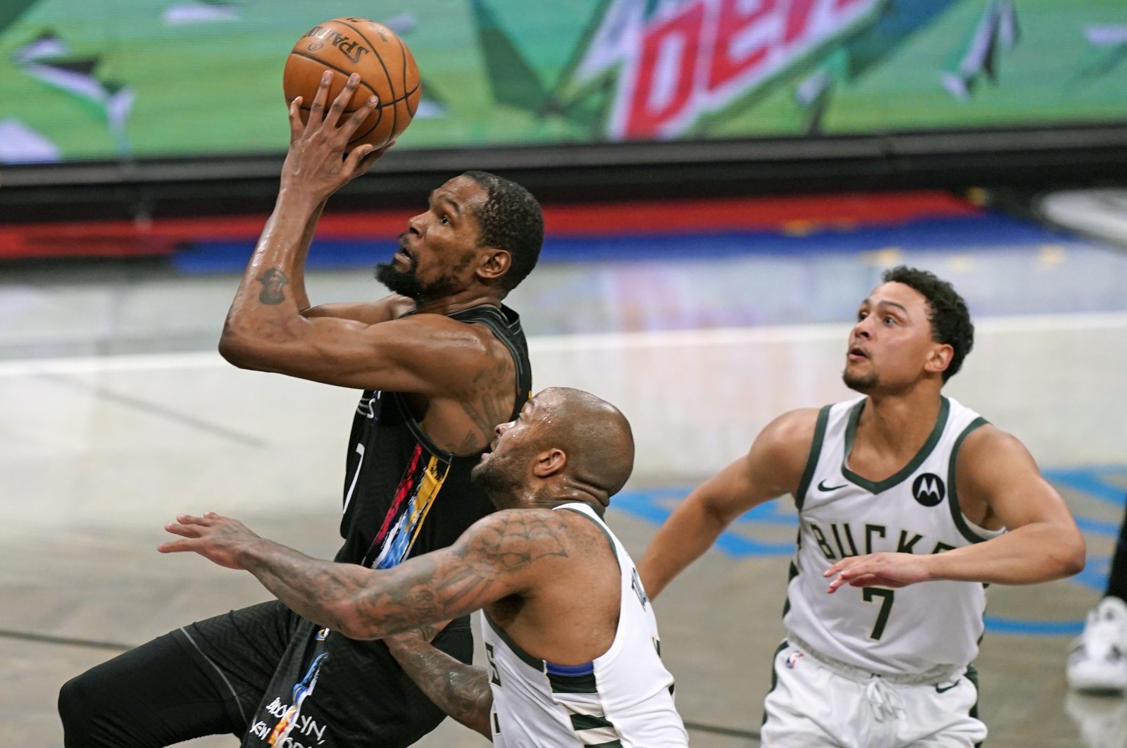 Brooklyn Nets forward Kevin Durant (L) goes up to shoot as Milwaukee Bucks forward P.J. Tucker (C) and guard Bryn Forbes (R) look on during Game 2 of their NBA second-round playoffs, June 7, 2021, New York, U.S. (AP Photo)