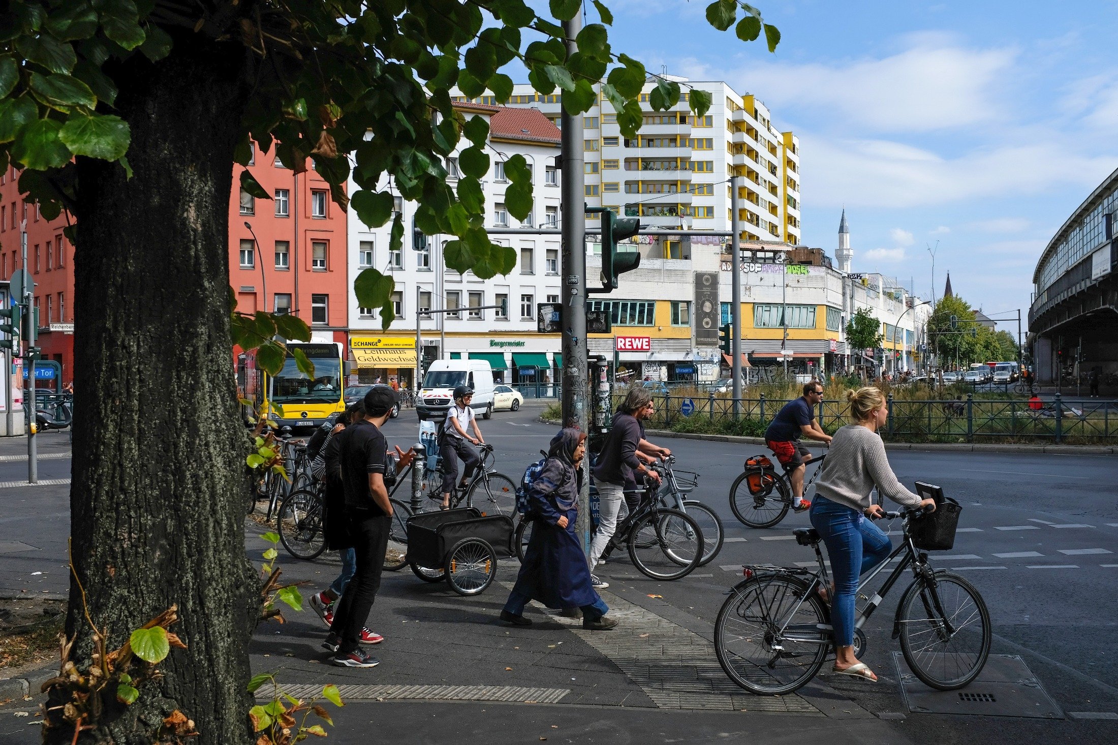 Pedestrians and bicyclists cross Skalitzer Strasse at Kottbuser Tor with a mosque