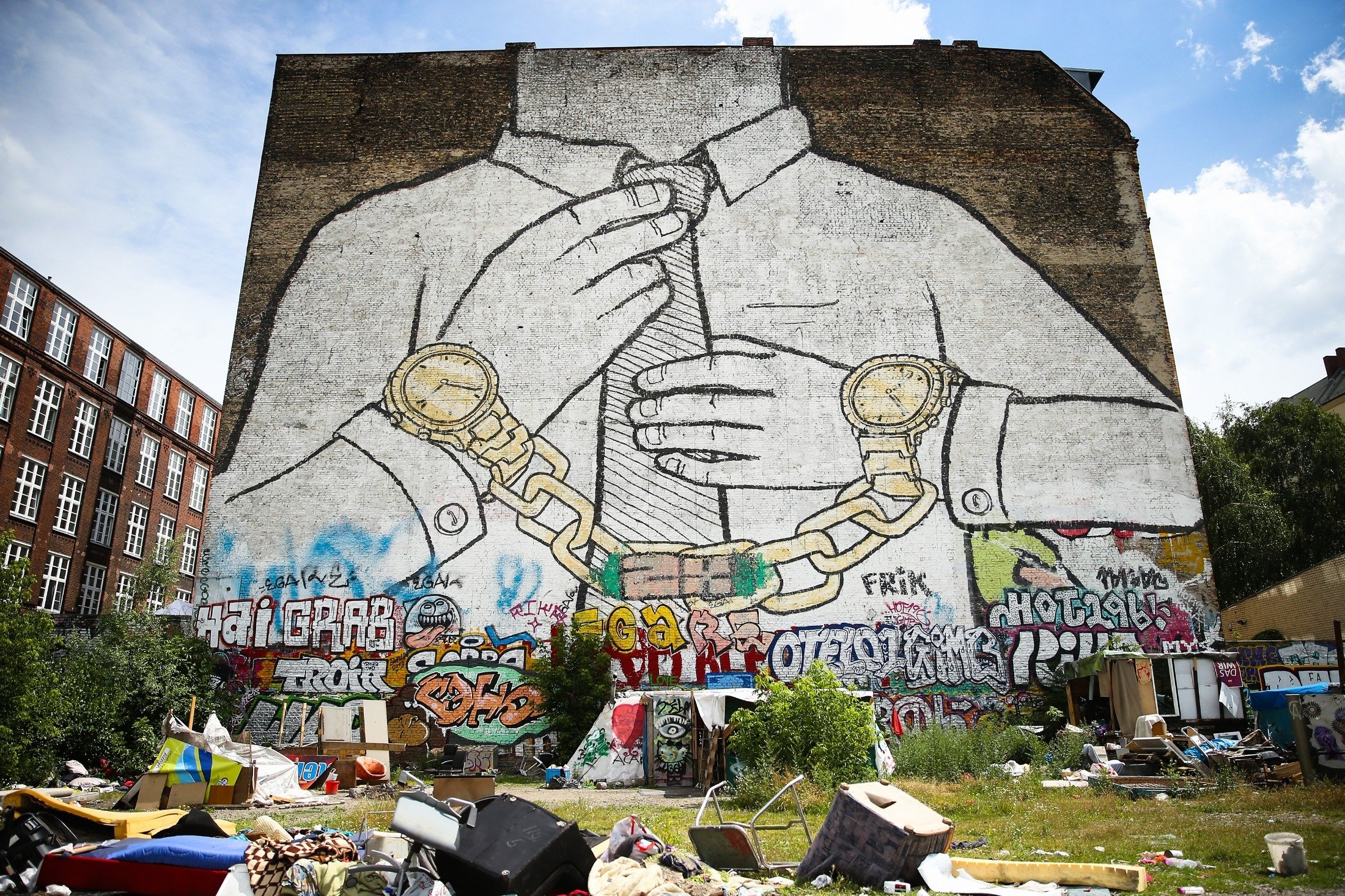A giant mural depicting a figure wearing a tie and chained to two wristwatches looms over the Cuvrystrasse squat in Kreuzberg district in Berlin, Germany, June 26, 2014. (Getty Images)