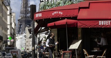 A waiter serves beverages on a cafe's terrace near the Eiffel Tower during the reopening of restaurant terraces and bars, Paris, France, May 19, 2021. (EPA-EFE Photo)