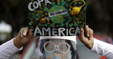 A woman holds a sign to protest against Brazil holding the Copa America in Brasilia, Brazil, Sunday, June 6, 2021. (AP Photo)