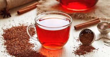 A cup of healthy traditional herbal rooibos tea with spices on a vintage wooden table. (Shutterstock Photo)