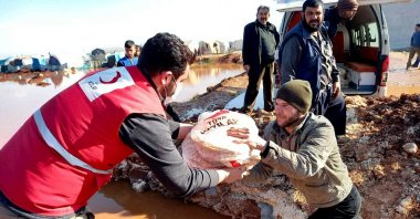 A Turkish Red Crescent worker hands over food to Syrians affected by floods in Idlib, Syria, Jan. 21, 2021. (AA PHOTO) 