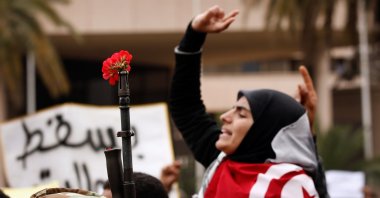 A Tunisian demonstrator makes a peace sign next to a flower in the barrel of a gun during a mass protest for changes in Tunisia's new government, in Tunis, Tunisia, Jan. 20, 2011. (Photo by Getty Images)