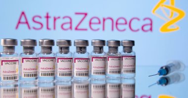Vials labelled "Astra Zeneca COVID-19 Coronavirus Vaccine" and a syringe are seen in front of a displayed AstraZeneca logo, March 14, 2021. (Reuters Photo)