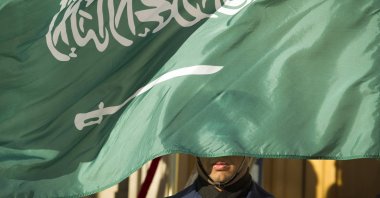 A guard member is covered by the flag of Saudi Arabia in Washington D,C., U.S., June 15, 2021. (AP Photo)