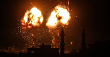 Explosions light up the night sky above buildings in Gaza City as Israeli forces shell the Palestinian enclave, early on June 16, 2021. (AA Photo)