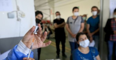 A health care worker prepares a COVID-19 shot as workers at a factory wait for their jabs, in Kırklareli, northwestern Turkey, June 16, 2021. (AA PHOTO)