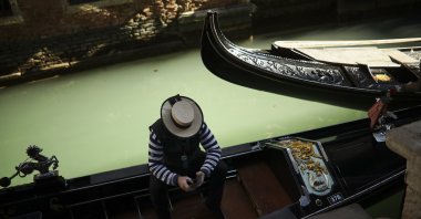 A gondolier looks at his smartphone as he waits for clients in Venice, Italy, Feb. 28, 2020. (AP Photo)