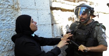 An Israeli police officer and a Palestinian woman scuffle during clashes that erupted ahead of a planned march by Jewish ultranationalists through East Jerusalem, outside Jerusalem's Old City, Tuesday, June 15, 2021. (AP Photo)
