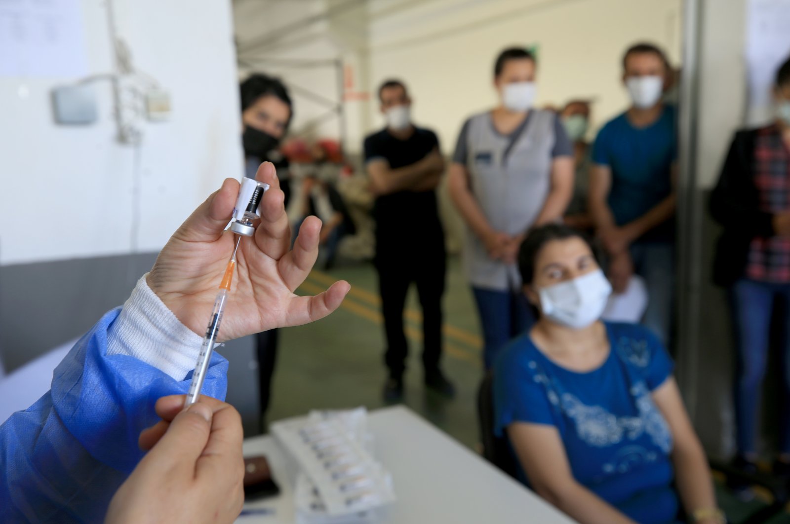 A health care worker prepares a COVID-19 shot as workers at a factory wait for their jabs, in Kırklareli, northwestern Turkey, June 16, 2021. (AA PHOTO)