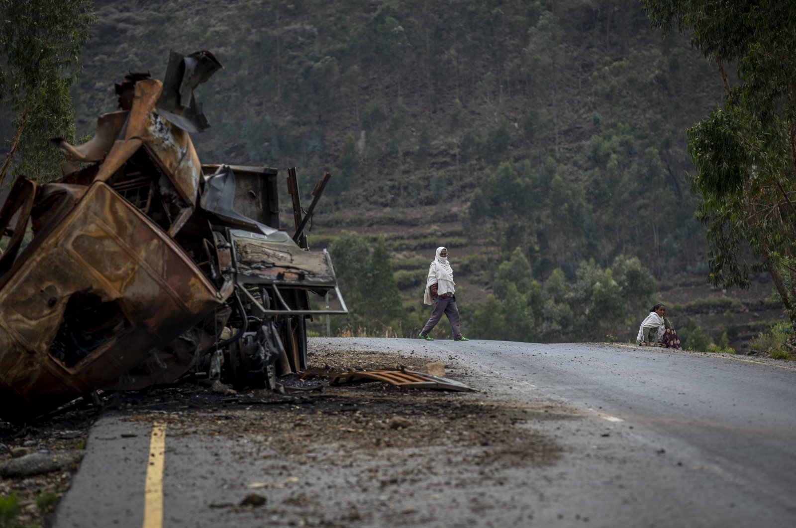 A man crosses near a destroyed truck on a road leading to the town of Abi Adi, in the Tigray region of northern Ethiopia, May 11, 2021. (AP Photo)