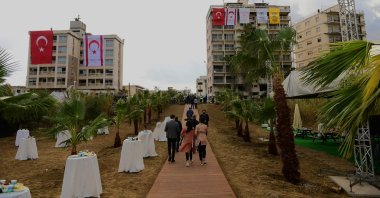 People walk in front of abandoned buildings adorned with Turkish and Turkish Cyprus flags before Turkish President Recep Tayyip Erdoğan inspects the newly opened beachfront of Varosha, Turkish Cyprus, Nov. 15, 2020. (AP Photo)