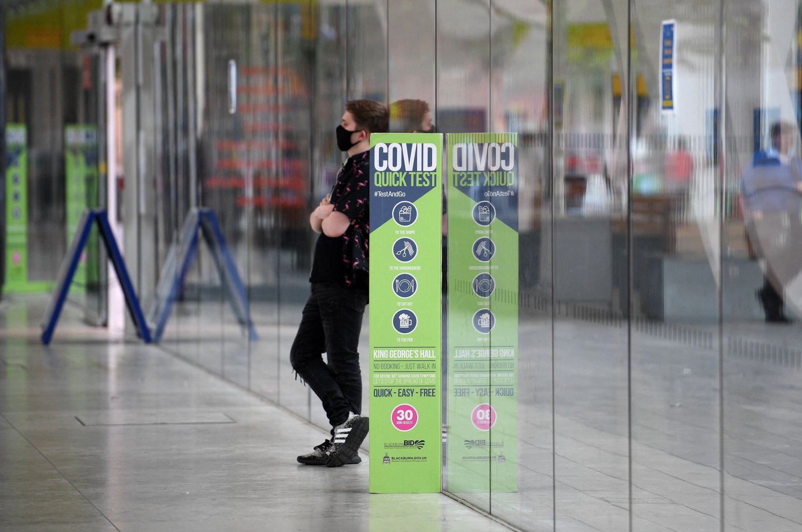 A man wearing a face-covering stands by a COVID-19 information sign near the Bus Station in Blackburn, northwest England, June 16, 2021. (AFP Photo)