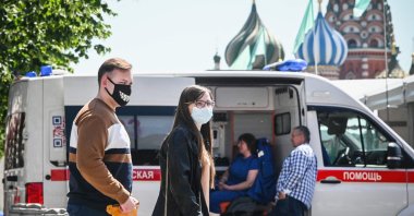 People wearing face masks walk along Red Square in front of St. Basil's cathedral in central passing an ambulance amid the crisis linked with the COVID-19 pandemic caused by the novel coronavirus, Moscow, Russia, June 18, 2021. (AFP Photo)
