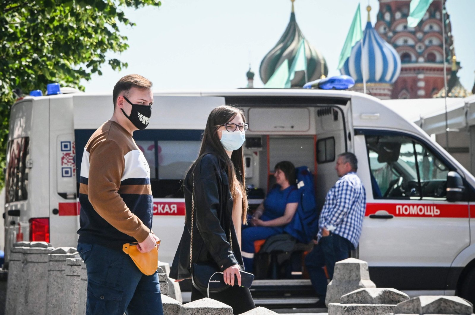 People wearing face masks walk along Red Square in front of St. Basil's cathedral in central passing an ambulance amid the crisis linked with the COVID-19 pandemic caused by the novel coronavirus, Moscow, Russia, June 18, 2021. (AFP Photo)