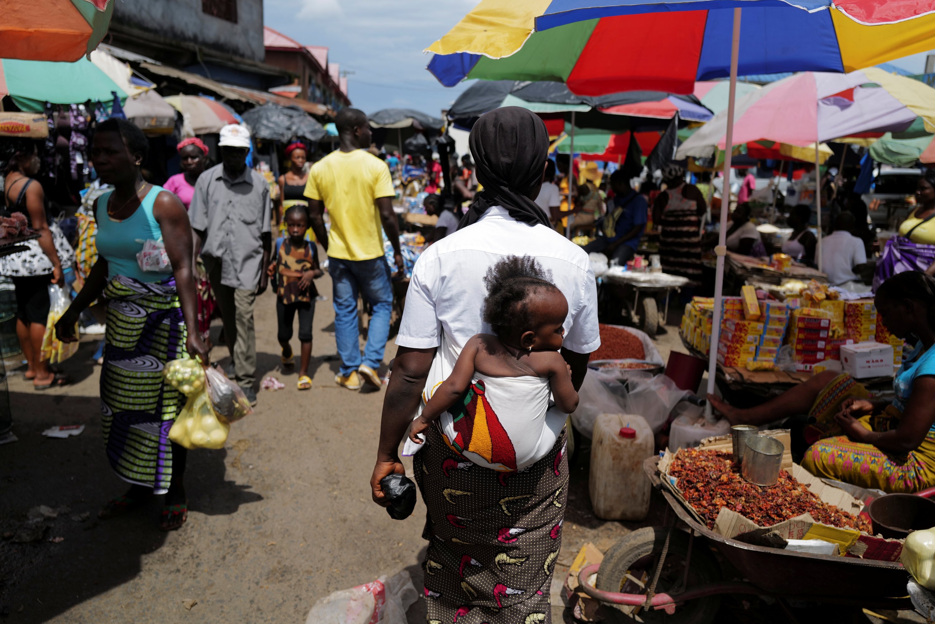 A woman carries her daughter as she walks at the Gobachop market in Monrovia, Liberia, June 7, 2021. (REUTERS)