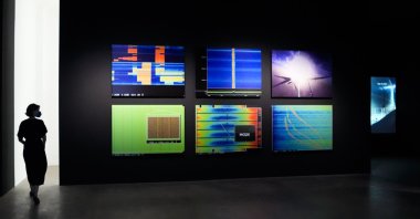 A woman walks through an exhibition by American artist and filmmaker Laura Poitras, near the art work "Anarchist" by Laura Poitras in collaboration with Henrik Moltke, at the N.K.B. gallery in Berlin, Germany, June 18, 2021. (AP Photo)