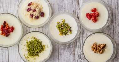 A range of Turkish muhallebi dessert, a kind of pudding, are adorned with different pistachios, nuts and sweets. (Shutterstock Photo)