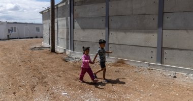 Children walk next to a newly built concrete wall inside the Ritsona camp for refugees and migrants, in Greece, June 15, 2021. (Reuters Photo)
