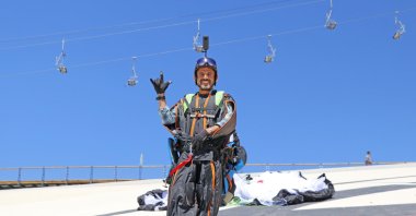 Cengiz Koçak dons his wingsuit after his workday ends on Babadağ mountain, Muğla province, southwestern Turkey, June 19, 2021. (AA PHOTO)