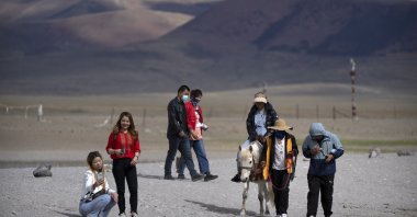 Tourists walk along the lakeshore and ride a pony in Namtso in western China's Tibet Autonomous Region, China, June 2, 2021. (AP Photo)
