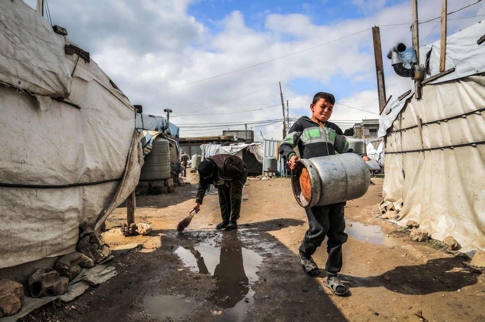A Syrian refugee clears rainwater outside her tent following heavy rain, at Marj Syrian refugee camp in Lebanon's Bekaa valley, Feb. 20, 2021 (Getty Images)