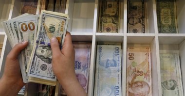 A money changer counts U.S. dollar bills, with Turkish lira banknotes in the background, at a currency exchange office in central Istanbul, Turkey, Aug. 21, 2015. (Reuters Photo)