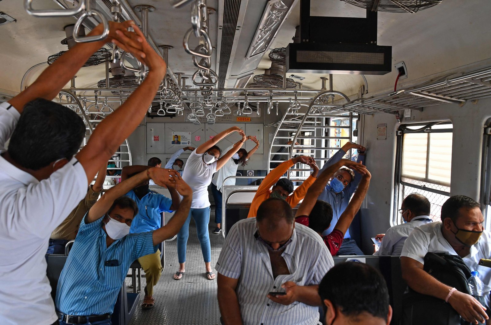 Commuters take part in a yoga session inside a train coach to mark International Yoga Day in Mumbai, India, on June 21, 2021. (AFP Photo)