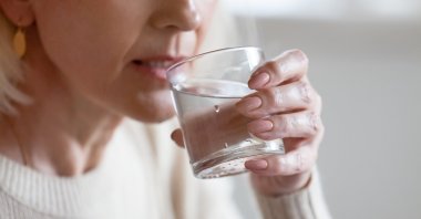 A woman drinks a glass of water. (Shutterstock Photo)