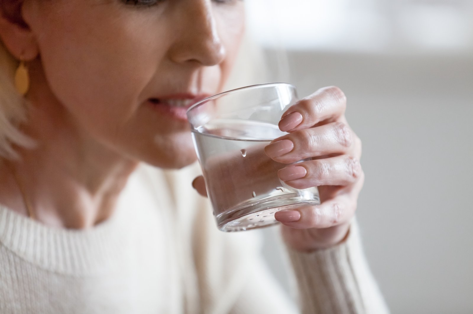 A woman drinks a glass of water. (Shutterstock Photo)