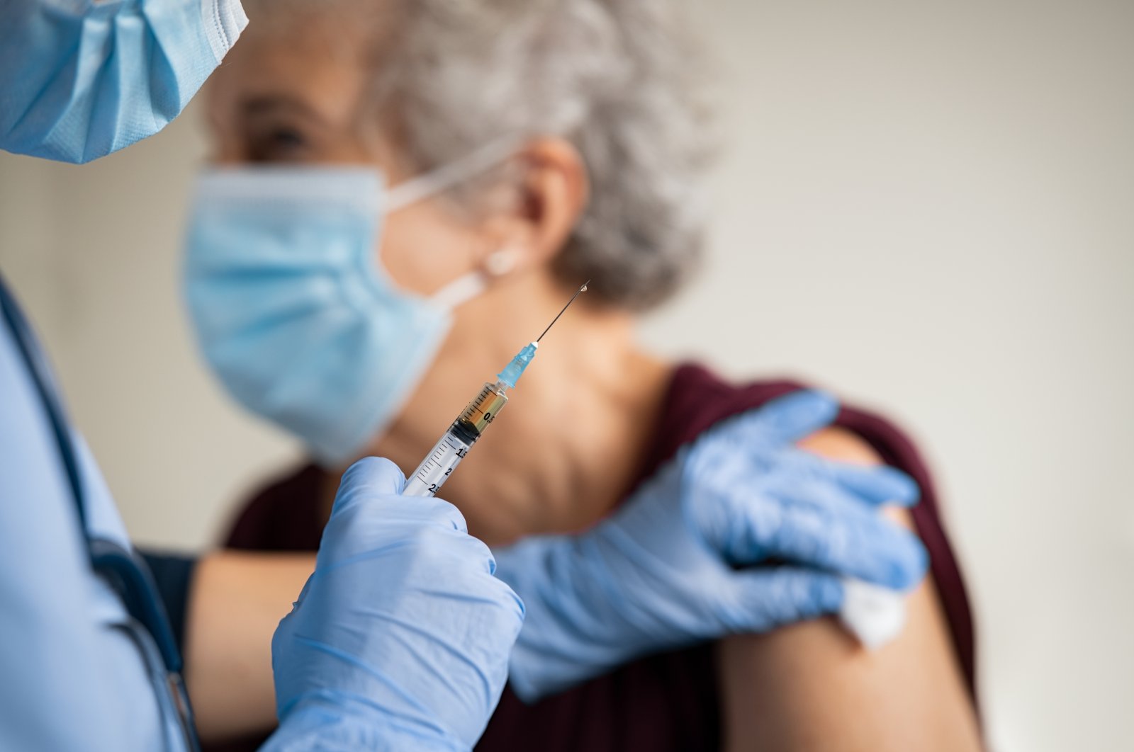 A young nurse administers an injection to an elderly woman. (Shutterstock Photo)