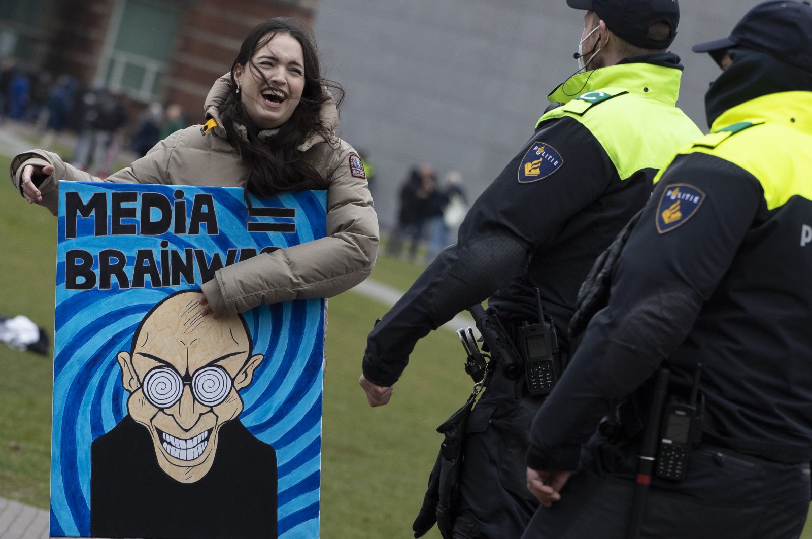 Dutch police talk to a demonstrator with a painting reading "Media = Brainwash" prior to breaking up a demonstration against coronavirus-related government policies in Amsterdam, The Netherlands, March 28, 2021. (AP Photo)