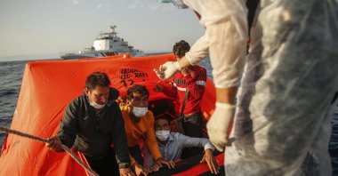 Turkish coast guard officers on their vessel, wearing protective gear to help prevent the spread of coronavirus, talk to migrants on a life raft after they were pushed back by the Greek coast guard in the Aegean Sea, between Turkey and Greece, Sept. 12, 2020. (AP File Photo)
