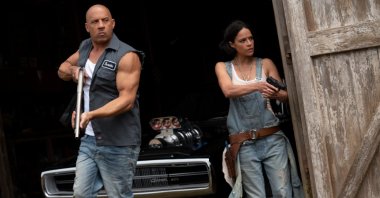 Vin Diesel (L), and Michelle Rodriguez walk out of a barn holding weapons, in a scene from the movie "F9: The Fast Saga." (Universal Pictures via AP)