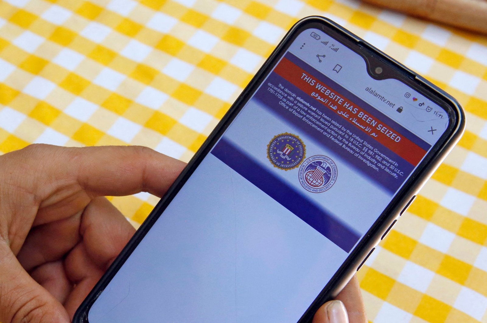 An Iranian man reads on his mobile phone a statement declaring Iran's Arabic-language channel Al-Alam's website 'has been seized' by the U.S. government, in Tehran, Iran, June 23, 2021. (AFP Photo)