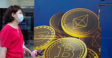 In this June 1, 2021, file photo, a woman walks past an advertisement for Bitcoin in Hong Kong. (AP Photo)