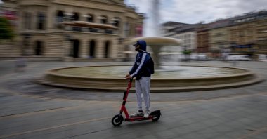 A man riding an e-scooter passes in front of the Old Opera in Frankfurt, Germany, June 22, 2021. (AP Photo)