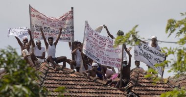Death-row inmates of Sri Lanka's Welikada prison protest holding banners from the roof of the prison in Colombo, Sri Lanka, Friday, June 25, 2021. (AP Photo)