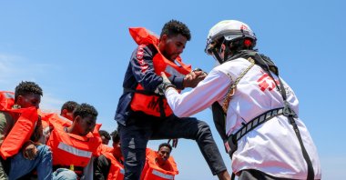 A member of the Doctors Without Borders (MSF) helps a migrant off a boat in the Mediterranean Sea, June 12, 2021. (Reuters Photo)