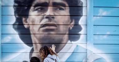 A woman and her children look at a mural of Diego Armando Maradona, as they commemorate 35 years of the goal that the Argentine star scored against England in the Mexico 1986 World Cup, in Buenos Aires, Argentina, June 22, 2021. (EPA Photo)