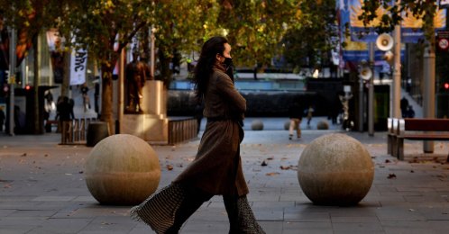 A woman wearing a face mask walks along a street in the central business district of Sydney as authorities locked down several central areas of Australia's largest city to contain an outbreak of the highly contagious delta variant, Sydney, Australia, June 25, 2021.  (AFP Photo)
