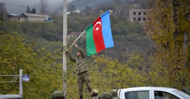 An Azerbaijani soldier fixes the national flag on a lamp post in the town of Lachin, Azerbaijan, on Dec. 1, 2020. (AFP Photo)