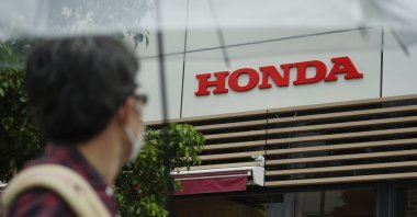 A man wearing a protective mask walks past the logo of Honda Motor Company, in Tokyo, Japan, May 13, 2021. (AP Photo)