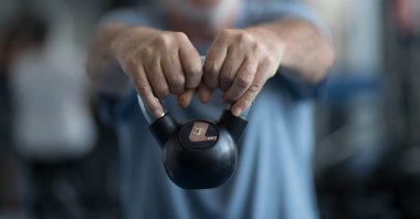 An elderly man holding a weight at the gym. (Shutterstock Photo) 