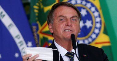 Brazil's President Jair Bolsonaro holds his protective face mask during a ceremony at the Planalto Palace, amid the coronavirus pandemic, in Brasilia, Brazil, June 10, 2021. (Reuters Photo)