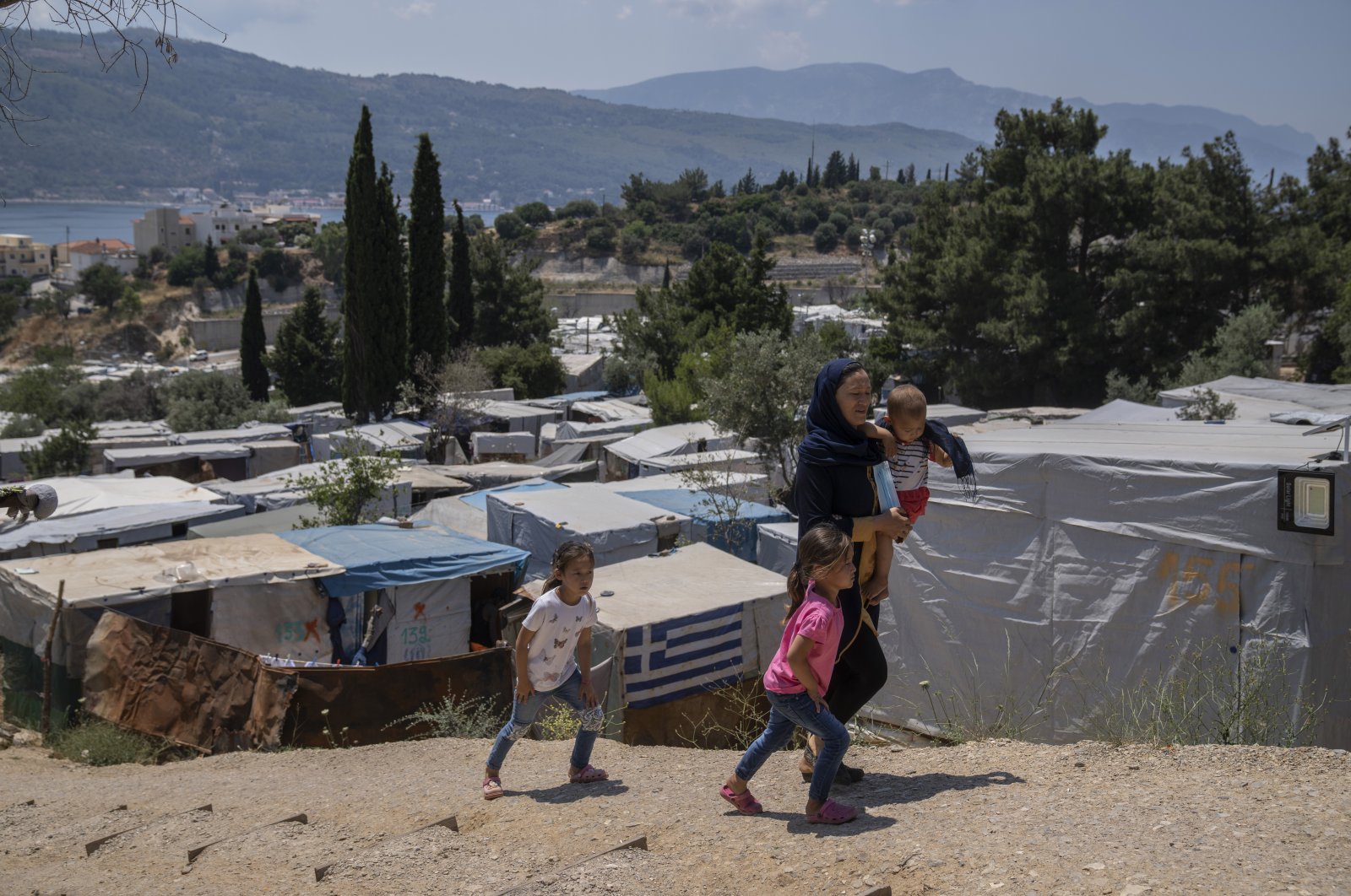 An Afghan woman and her three children walk outside the perimeter of the refugee camp at the port of Vathy on the eastern Aegean island of Samos, Greece, June 11, 2021. (AP Photo)