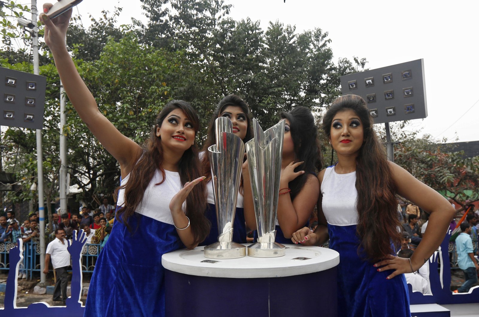 Models take a selfie next to the World Twenty20 trophies after they arrived in Kolkata, India, Feb. 24, 2016. (Reuters Photo)